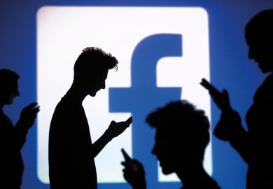 Silhouettes of people using smartphones in front of Facebook logo
