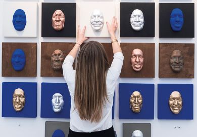 A woman with her back to the camera places a number of differently coloured face masks on a wall