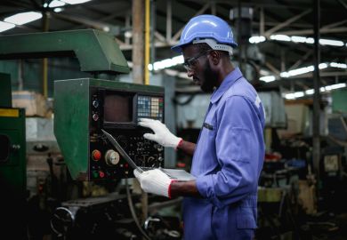 factory worker in using laptop and push buttons to test the machine operation after maintenance