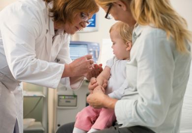 Female doctor administering vaccine to small child