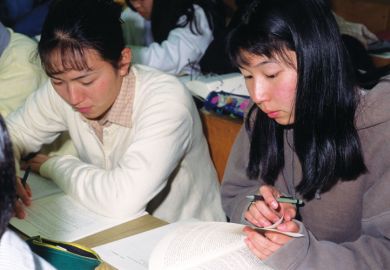 Female Japanese students reading textbooks Female Japanese students reading textbooks