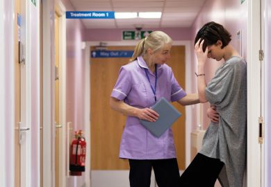 Female nurse comforts young woman in hospital corridor