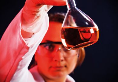 Female scientist examining flask of liquid