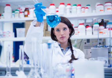 Female scientist examining liquid in flask