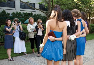 Female students being photographed by their mothers and sister before senior prom