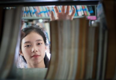 Female student holding book in library