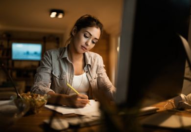 Female student taking notes while learning at night at home