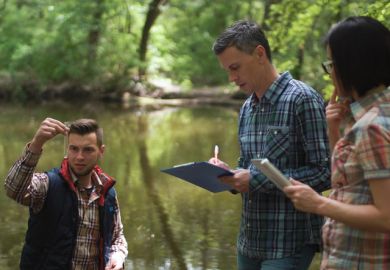 Three scientists examine lake water during fieldwork