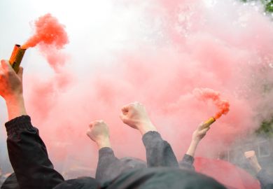 Dutch football fans clench fists and hold orange flares
