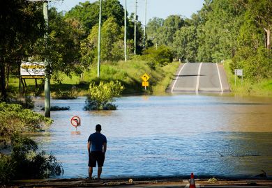 A stranded resident looks at a road, submerged under floodwaters in Queensland. To illustrate that domestic enrolments in Australian universities risk bypassing the areas of greatest need, as regional universities experience a decline in enrolments.