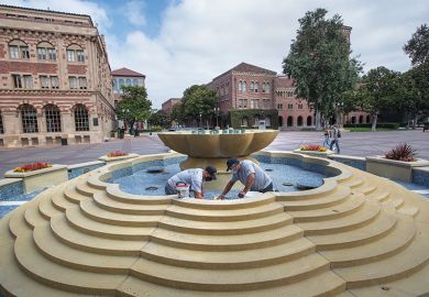 Men repair damaged tiles inside a fountain on the USC campus in Los Angeles