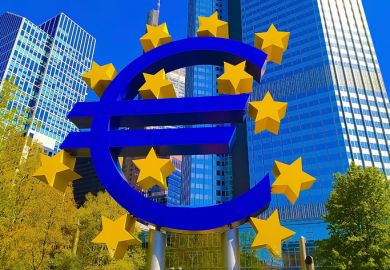 Frankfurt, Germany - April 24, 2022 Euro sign sculpture in a park among modern office towers in Frankfurt