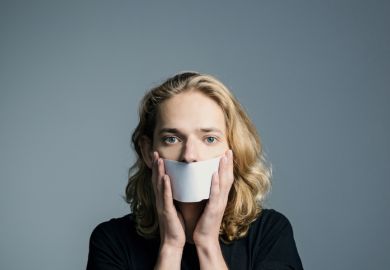 A man holds paper in front of his mouth, symbolising non-disclosure agreements