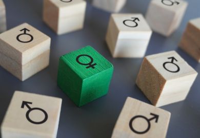 Female symbol surrounded by male symbol on wooden blocks, symbolising gender discrimination