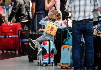 Travellers sit on their suitcases at the check-in counters