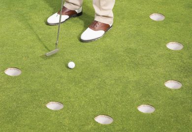 Golfer putting on green with multiple holes