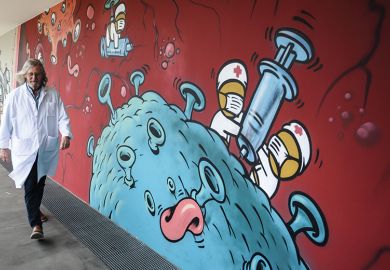 French microbiologist Didier Raoult walking past a wall of Covid graffiti