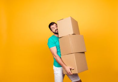 Grimacing courier is trying to keep big stack of cardboard boxes in his hand