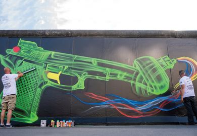 Street artists create an updated likeness of Swedish artist Carl Fredrik Reuterswaerd’s famous “Knotted Gun” sculpture on a segment of the former Berlin Wall, 2020
