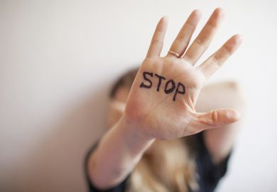 A woman with "stop" written on her palm, symbolising harassment