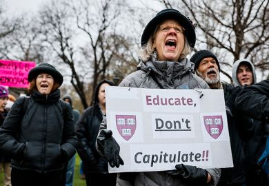 A protester holds a sign reading "Educate, Don't Capitulate!!" during a rally at Cambridge Common to urge Harvard to resist President Trump's influence on the institution, 12 April 2025. A protester holds a sign reading "Educate, Don't Capitulate!!" during a rally at Cambridge Common to urge Harvard to resist President Trump's influence on the institution, 12 April 2025.