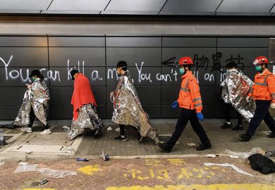 Hong Kong students walk past graffiti