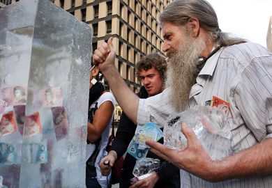 People chip at ice block to reach money frozen inside