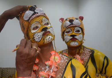 Indian dancers apply tiger face paint, as an illustration of credibility problems in India's universities.