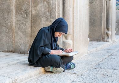 An Iranian student sits on the ground, illustrating inequliaty in university entrance
