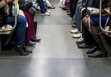 Feet of people sitting opposite each other in a subway car.