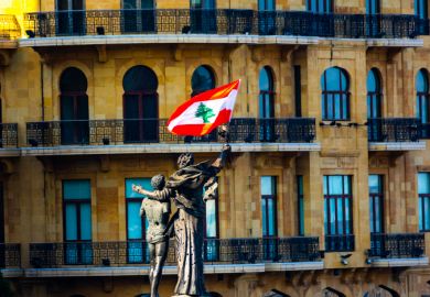 A statue of two people hugging with a Lebanese flag attached