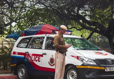 Delhi, India: A policeman in front of a red and white mini van patrolling the state border of the Delhi, state. Delhi, India: A policeman in front of a red and white mini van patrolling the state border of the Delhi, state.