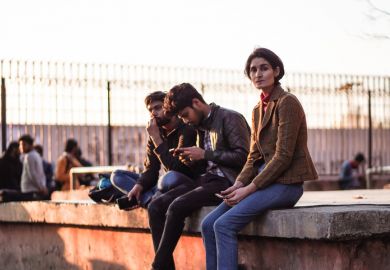 Group of young male and female students sitting inside the university campus of Jamia Millia Islamia entrance door.