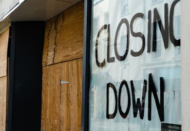 Closing down sign in a boarded-up shop window