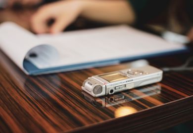 A tape recorder sits next to a pad of paper on a desk