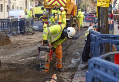 Man in yellow vest drilling the pavement in a London Street. Man in yellow vest drilling the pavement in a London Street.