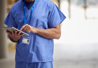Close Up Of Male Medical Worker In Scrubs With Digital Tablet In Hospital