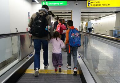 Air travellers walk on a moving walkway or travellator through Heathrow Airport.