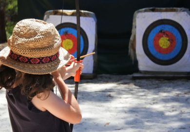 Young girl archer aiming to target.