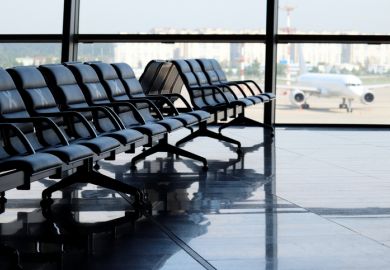 Empty waiting chairs in the airport building against the plane on runway 