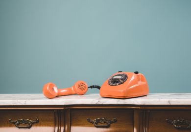 View of an old retro telephone with the receiver off the hook on a table