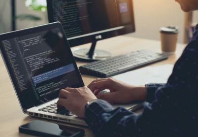 Man sits at desk, typing into a laptop Man sits at desk, typing into a laptop