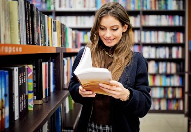 A stock image of a woman reading a book in a library 