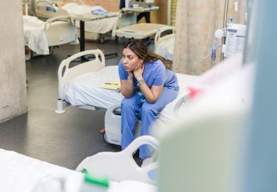 A doctor sits on an empty bed looking worried A doctor sits on an empty bed looking worried