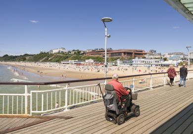 Old man on a mobility scooter on the promenade of Bournemouth Pier