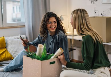 Two young women unpacking in a room