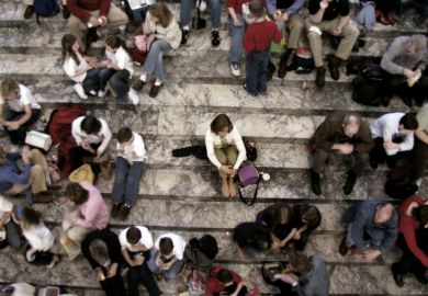 Woman sits alone on steps with everyone else in groups
