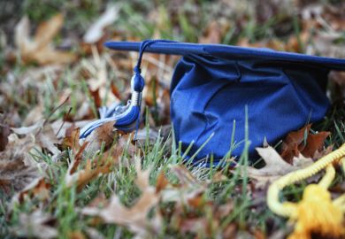Graduation cap on ground among leaves