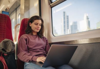 Student commuter on laptop on train