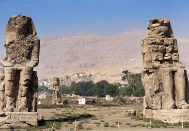 Colossi of Memnon, Luxor, River Nile, Egypt. Two massive stone statues of the Pharaoh stand at the front of the ruined Mortuary Temple of Amenhotep III